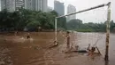 Anak-anak bermain di lapangan sepak bola di kawasan Kemang, Jakarta, Kamis (16/11). Tingginya intensitas hujan dan pesatnya pembangunan menyebabkan kawasan tersebut langganan banjir yang berasal dari luapan Kali Krukut. (Liputan6.com/Immanuel Antonius)
