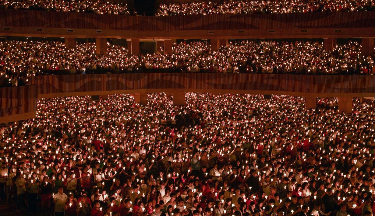 Diiringi nyala puluhan ribu lilin, suasana perayaan Natal di Gereja Bethany Nginden Surabaya menjadi khidmat dan penuh penghayatan. Tampak dalam foto, umat Kristiani menyalakan lilin selama misa Hari Natal di Gereja Bethany, Surabaya, Jawa Timur pada Kamis 25 Desember 2025. (JUNI KRISWANTO/AFP)