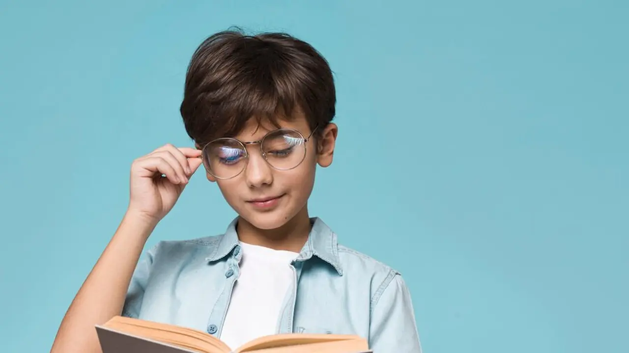 Seorang anak laki-laki sedang memegang kacamata sambil membaca buku (Foto Dok: Freepik/freepik)