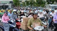 Para pengendara motor melintasi persimpangan jalan di pusat kota Hanoi, 4 Juli 2017. Ibu Kota Vietnam akan melarang sepeda motor di distrik metropolitan mulai 2030 guna mengurangi kemacetan lalu lintas dan polusi. (AFP PHOTO/HOANG DINH Nam)