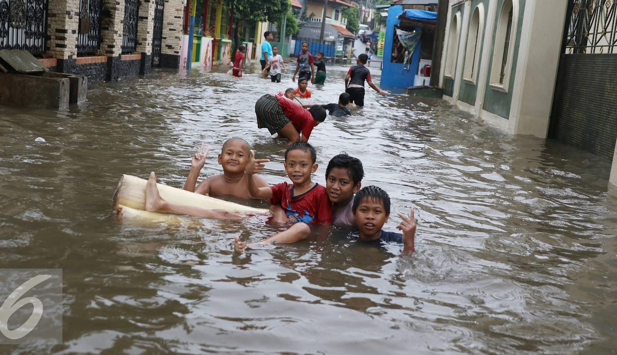  Anak-anak bermain saat banjir menggenangi Jalan Ketapang di kawasan Pasar Minggu, Jakarta, Selasa (4/10). Banjir yang berasal dari luapan Kali Anur tersebut menyebabkan Jalan Ketapang tidak bisa dilewati kendaraan. (Liputan6.com/Immanuel Antonius)