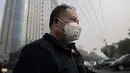 Seorang pria beraktivitas mengenakan masker pelindung untuk menghindari polusi udara buruk di Beijing (22/10). (AFP Photo/Nicolas Asfaouri)