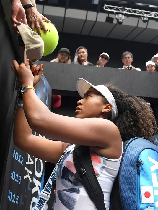 Petenis Jepang Naomi Osaka menandatangani topi yang disodorkan penonton usai mengalahkan petenis Republik Ceko Marie Bouzkova pada Australia Terbuka di Melbourne, Australia, Senin (20/1/2020). Penonton menyodorkan topi, bendera, hingga bola untuk ditandatangani Naomi. (AP Photo/Andy Brownbill)