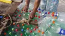 Nelayan Palestina, Mouad Abu Zeid memperbaiki perahunya yang terbuat dari botol plastik bekas di pantai Rafah, Jalur Gaza, 14 Agustus 2018. Zeid menggunakan lem dan jaring bekas untuk mengikat botol menjadi perahu kecil. (AFP/SAID KHATIB)