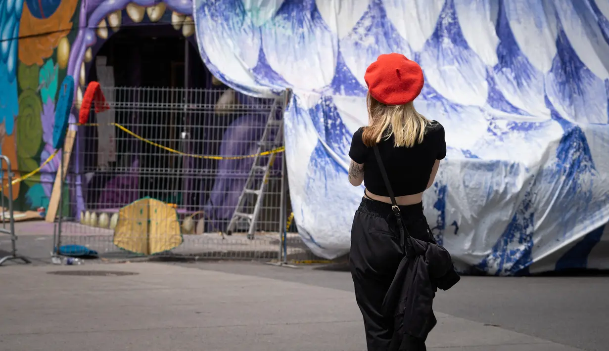Pengunjung menyaksikan karya seni yang dilukis saat Festival Mural Montreal di Quebec, Kanada, 16 Juni 2022. Sebanyak 21 seniman melukis mural baru tahun ini. (Paola Chapdelaine/AFP)
