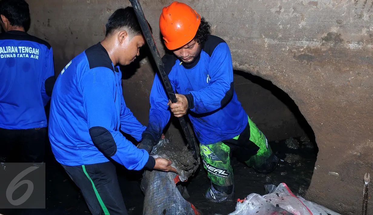 Petugas Dinas Tata Air dan petugas PPSU memasukkan lumpur ke dalam karung saat aksi pembersihan gorong-gorong di depan Istana Merdeka, Jakarta, Kamis (3/3). Aksi pembersihan ini menyusul temuan kulit kabel di gorong-gorong. (Liputan6.com/Gempur M Surya)