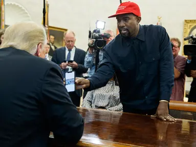 Rapper Kanye West menunjukkan foto pesawat hidrogen kepada Presiden AS, Donald Trump selama pertemuan di Oval Office, Gedung Putih, Kamis (11/10). West diundang untuk makan siang guna membahas reformasi penjara dan masalah lainnya. (AP/Evan Vucci)