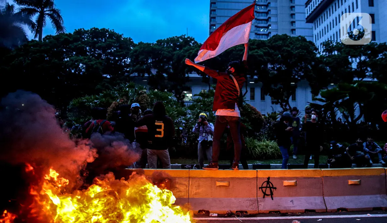 Sejumlah pendemo berswafoto di kobaran api saat aksi unjuk rasa di kawasan patung kuda, Jakarta, Selasa (20/10/2020). Gelombang protes tolak UU Cipta Kerja belum surut sejak beleid kontoversial itu disahkan pemerintah dan DPR pada 5 Oktober lalu. (Liputan6.com/Faizal Fanani)