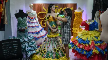 Dalam foto yang diambil pada tanggal 12 September 2024 ini, Leonora Buenviaje (kanan) menyiapkan gaun yang terbuat dari bahan daur ulang untuk Maria Theresa Deligero (kiri), di rumahnya di Cainta, provinsi Rizal, Filipina. (JAM STA ROSA/AFP)