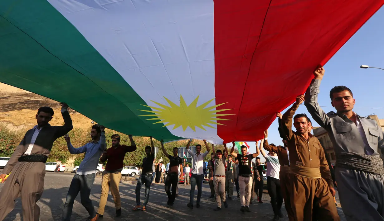 Etnis Kurdi Irak membentangkan bendera Kurdi saat melakukan aksi untuk meminta referendum kemerdekaan di Arbil, Irak utara (13/9). Mereka meminta referendum untuk menentukan kemerdekaan etnis Kurdi di Irak. (AFP Photo/SAfim Hamed)