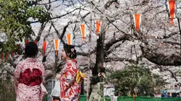 Pengunjung berpakaian Kimono melihat bunga sakura yang mekar di taman Tokyo, Jepang, Jumat (23/3). Mekarnya sakura menjadi momen yang paling ditunggu oleh para turis asing di Jepang. (Foto AP/Eugene Hoshiko)