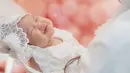 Fotografer tak sengaja memotret, Baby Kimova yang pamer senyuman manis sampai matanya ikut tersenyum ketika sedang tidur ini dipuji cantik oleh netizen. Pake baju putih lengkap dengan jilbab mininya, Baby Kimova semakin gemas. Tak sedikit netizen berkomentar dan menyebut jika foto tersebut adalah foto favorit dari sederet foto momen akikah Baby Kimova. (Liputan6.com/IG/@vicymelanie)