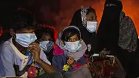 Perempuan dan anak-anak etnis Rohingya duduk dekat api unggun setelah kapal mereka terdampar di Pulau Idaman, Aceh Timur, Aceh, Jumat (4/6/2021). Kapal yang mengangkut 81 pengungsi Rohingya terdampar di Pulau Idaman. (AP Photo/Zik Maulana)