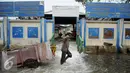 Seorang warga melitasi banjir yang menggenangi Kawasan Muara Angke, Jakarta, Rabu (11/1). Banjir yang terjadi hampir setiap hari dalam satu bulan terakhir akibat rob yang diperparah dengan jebolnya tanggul. (Liputan6.com/Gempur M. Surya)