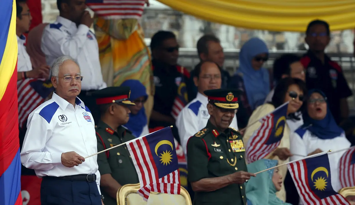 PM Najib Razak (kiri) mengibarkan bendera nasional Malaysia saat merayakan Hari Kemerdekaan ke-58 di Kuala Lumpur, Senin (31/8/2015).  Perayaan kemerdekaan kali ini dilakukan di tengah desakan mundur kepada PM Najib. (REUTERS/Olivia Harris)
