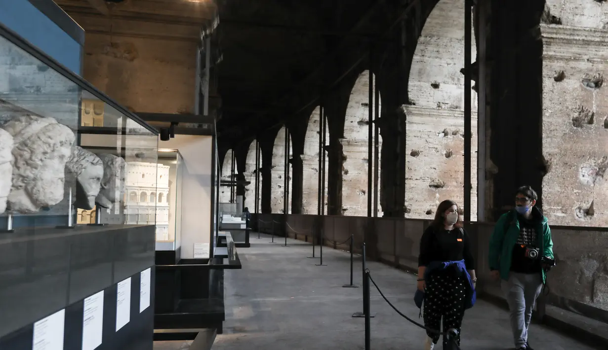 Para pengunjung berjalan di Colosseum di Roma, Italia (4/11/2020). PM Italia Giuseppe Conte telah menandatangani dekret yang menetapkan jam malam berskala nasional mulai pukul 22.00 sampai 05.00 setelah jumlah kasus coronavirus terus melonjak di negara itu. (Xinhua/Cheng Tingting)