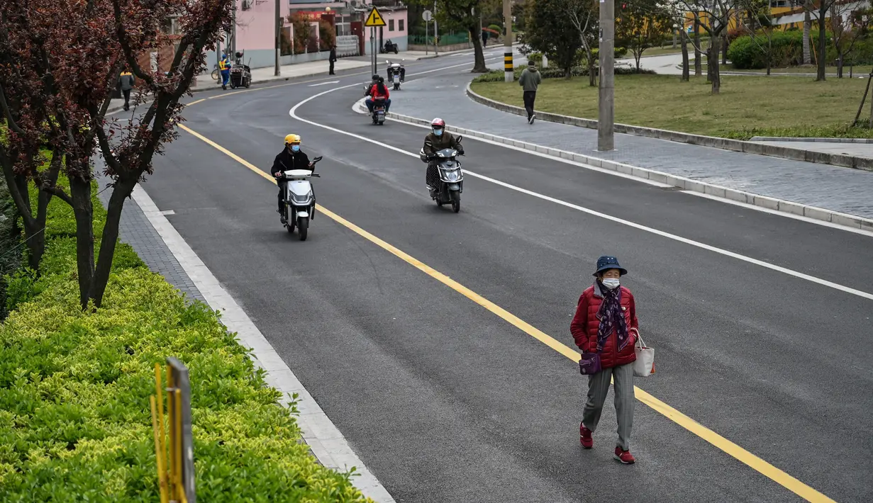 Seorang pria berjalan di jalan yang tenang di distrik Yangpu, di Shanghai (28/3/2022). Shanghai  lockdown setiap setengah kota secara bergiliran untuk tes Covid-19 massal mulai Senin (28/3/2022) di tengah lonjakan infeksi. (AFP/Hector Retamal)