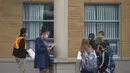 Seorang guru yang memakai masker dan pelindung wajah (kedua dari kiri) mengabsen para murid di luar sebuah sekolah di Mississauga, Ontario, Kanada (9/9/2020). Beberapa sekolah di Ontario dibuka kembali menawarkan kombinasi kelas tatap muka dan pembelajaran daring (online) bagi para murid. (Xinhua/Zo
