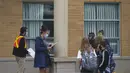 Seorang guru yang memakai masker dan pelindung wajah (kedua dari kiri) mengabsen para murid di luar sebuah sekolah di Mississauga, Ontario, Kanada (9/9/2020). Beberapa sekolah di Ontario dibuka kembali menawarkan kombinasi kelas tatap muka dan pembelajaran daring (online) bagi para murid. (Xinhua/Zo