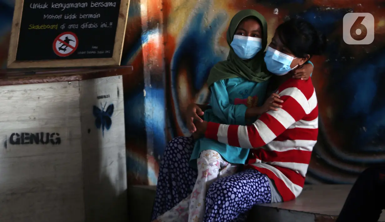 Warga bersama anaknya mengenakan masker di terowongan Kendal Jalan Blora, Jakarta, Jumat (25/6/2021). Hingga Jumat (25/6), Secara akumulatif Satgas Penanganan Covid-19 mencatat kasus positif Covid-19 di wilayah DKI Jakarta telah menyentuh angka 501.396 orang. (Liputan6.com/Helmi Fithriansyah)