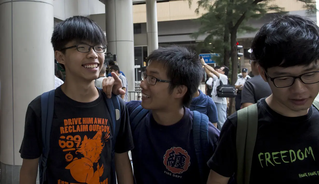 Joshua Wong (kiri) berbincang denga dua rekannya di luar pengadilan, Hong Kong, Cina, Jumat (28/8/2015). Joshua Wong, Nathan Law, dan Chow. Mereka dituntut atas tuduhan memanjat pagar kompleks gedung pemerintah pada awal demonstrasi. (REUTERS/Tyrone Siu)