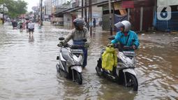 Pengendara motor mendorong kendaraannya melintasi genangan air ketika banjir merendam Jalan KH. Hasyim Ashari, Tangerang, Banten, Sabtu (16/7/2022). Hujan deras mengguyur sejak Jumat siang hingga Sabtu pagi. (Liputan6.com/Angga Yuniar)