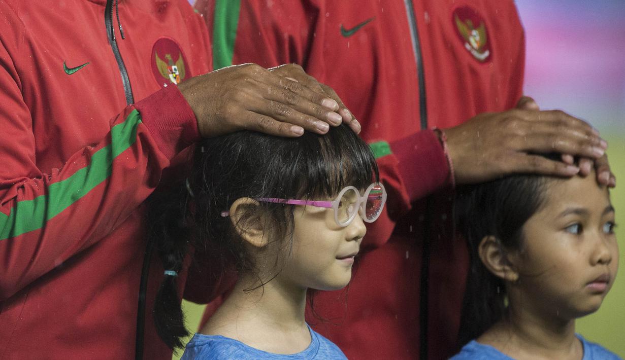 Tangan pemain Timnas Indonesia melindungi anak-anak dari hujan saat akan melawan Islandia pada laga persahabatan di SUGBK, Jakarta, Minggu (14/1/2018). Timnas Indonesia kalah 1-4 dari Islandia. (Bola.com/Vitalis Yogi Trisna)