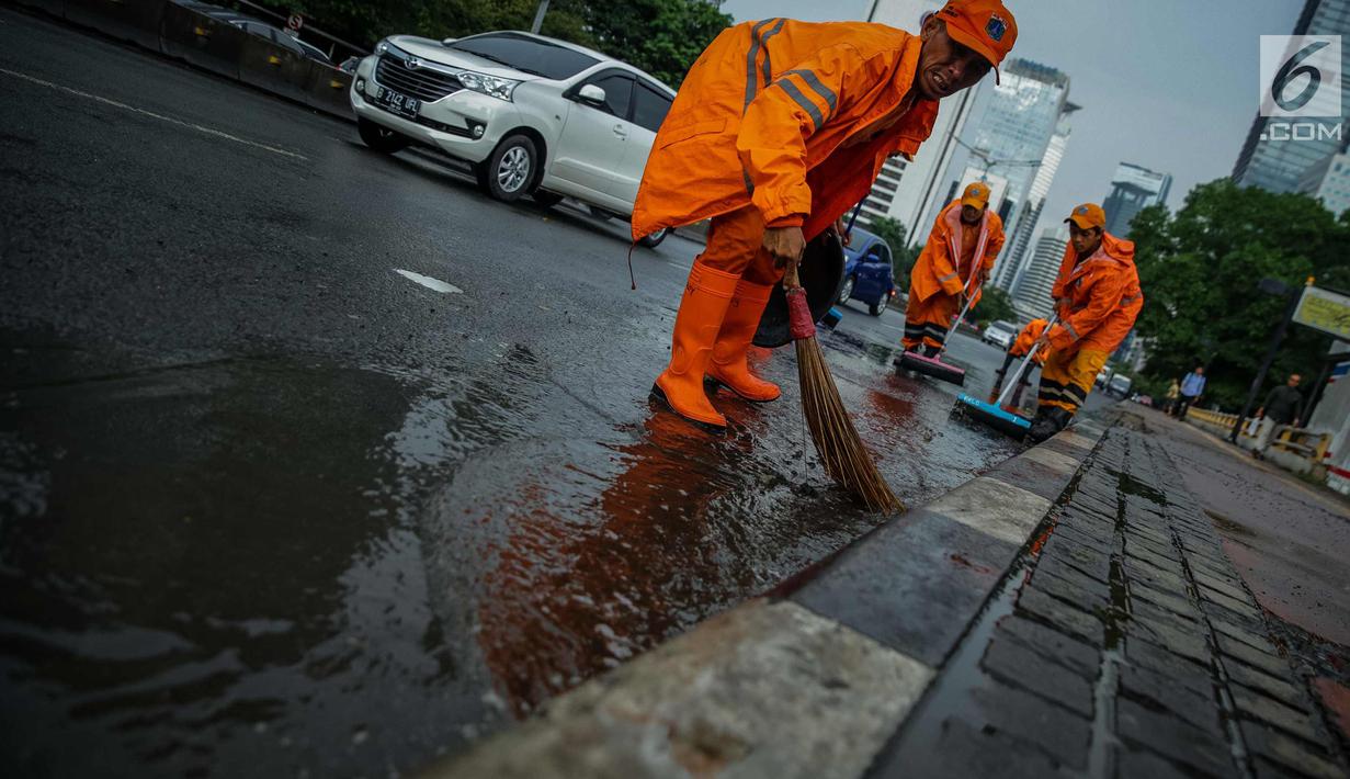 Petugas Dinas Kebersihan membersihkan genangan air usai hujan di kawasan jalan Sudirman, Jakarta, Rabu (22/11). Buruknya sistem drainase membuat petugas membersihkan genangan setiap kali hujan, meski dengan peralatan seadanya. (Liputan6.com/Faizal Fanani)