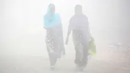 Warga berjalan melalui kabut tebal akibat polusi di Delhi, India (1/12). Sekitar 26 penerbangan ditunda atau dialihkan di Delhi sementara tiga dibatalkan, menurut situs IGI. (REUTERS/Cathal McNaughton)