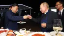 Presiden Rusia Vladimir Putin (kanan) dan Presiden China Xi Jinping (kiri) bersulang vodka saat menyantap pancake buatan bersama di sela acara Eastern Economic Forum di Vladivostok, Rusia, Selasa (11/9). (Sergei Bobylev/TASS News Agency Pool Photo via AP)