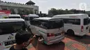 Seorang pewarta mengambil gambar mobil travel gelap yang disita di halaman Polres Metro Kabupaten Bekasi, Jawa Barat, Senin (10/5/2021). Satlantas Polres Metro Bekasi mengamankan 32 travel gelap yang masih beroperasi saat larangan mudik dari tanggal 6-17 Mei 2021. (Liputan6.com/Herman Zakharia)