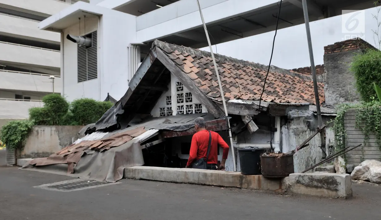 Chairul menuruni anak tangga untuk masuk ke rumahnya yang berada di halaman belakang apartemen Thamrin Executive Residence, Kebon Melati, Jakarta, Minggu (22/9/2019). Rumah itu menjadi satu-satunya yang bertahan di antara gedung-gedung tinggi yang dibangun sejak 2012. (merdeka.com/Iqbal S Nugroho)