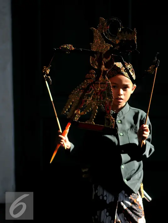 Seorang anak berpose dengan memegang sebuah wayang selama festival Dalang Bocah di Kawasan Kota Tua, Jakarta (20/11).  Festival akan berlangsung dari 20-22 November 2015. (Liputan6.com/Gempur M Surya)