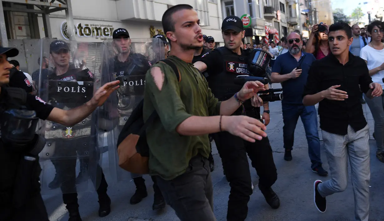 Polisi anti huru hara menahan seorang peserta yang berusaha mengikuti parade Gay Pride di pusat kota Istanbul, Minggu (25/6). Pihak berwenang Turki membatalkan parade gay di Istanbul setelah dilarang selama tiga tahun berturut-turut. (AP/Emrah Gurel)