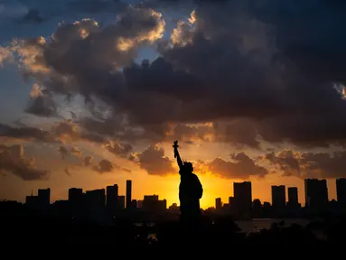 Replika Patung Liberty terlihat saat matahari terbenam di Odaiba, Tokyo, Jepang (29/7). Odaiba adalah sebuah pulau buatan di Teluk Tokyo, Jepang yang dihubungkan dengan pusat kota Tokyo dengan Jembatan Rainbow. (AFP Photo/Martin Bureau)