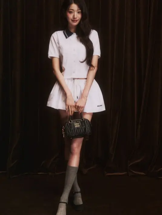 Wonyoung tampil super cute dengan setelan warna putih dari atasan kemeja lengan panjang berkerah hitam dan rok pendek. Ia mengenakan kaos kaki panjang dan stiletto heels hitam. [@for_everyoung10]