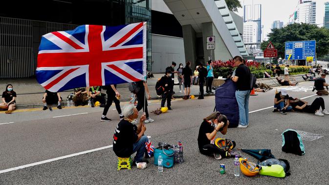 Seorang wanita memegang bendera Inggris ketika para demonstran beristirahat di sepanjang jalan utama dekat Gedung Dewan Legislatif saat menggelar protes terkait RUU Ekstradisi di Hong Kong, Senin (17/6/2019). (AP Photo/Vincent Yu)
