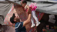 Abdullah Al-Hurkali bermain dengan putrinya, Tasneem, selama Hari Raya Idul Adha di sebuah kamp tenda untuk pengungsi Palestina di Khan Younis, Jalur Gaza, Rabu 27 Mei 2026. (AP Photo/Abdel Kareem Hana)