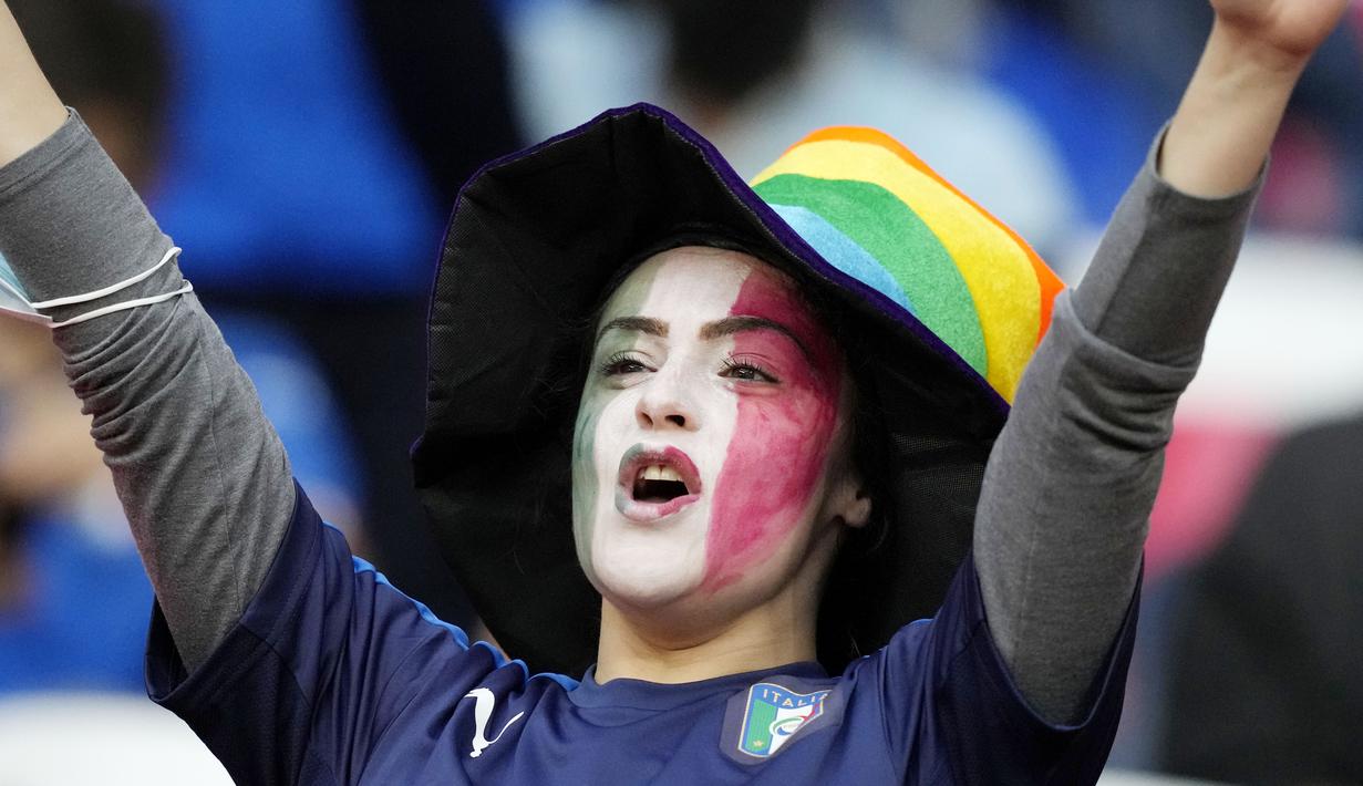 Suporter Timnas Italia mencat wajahnya dengan warna bendera nasionalnya saat menyaksikan pertandingan melawan Spanyol pada laga semifinal Euro 2020 di Stadion Wembley, Rabu (7/7/2021). (Foto:AP/Frank Augstein,Pool)