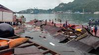 Orang-orang berdiri pada atap toko yang runtuh di pelabuhan setelah gempa magnitudo 5,1 di Jayapura, Provinsi Papua, Indonesia, 9 Februari 2023. Korban meninggal dalam gempa Jayapura adalah Rista (25), Ani (26), Astrid (25), dan Maya (27). (FAISAL NARWAWAN/AFP)