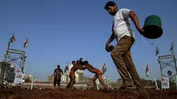 Panitia menyiram areal pertandingan Indian traditional wrestling competition atau Kushti di Arena Akhara, Mumbai, India, 20 Maret 2016.  Olahraga tradisional ini terus dilestarikan sebagai bagian dari budaya. (EPA/Divyakant Solanki)