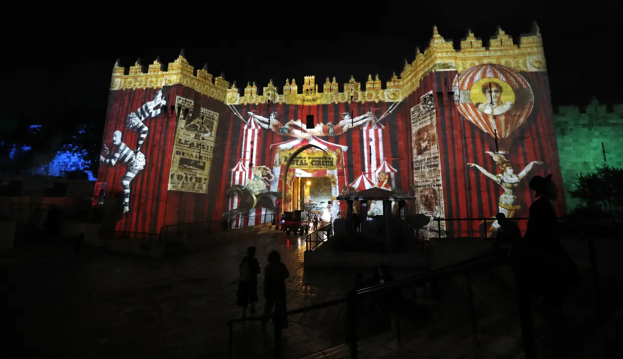 Orang-orang berjalan di dekat gerbang Damaskus selama festival cahaya di kota tua Yerusalem, 28 Juni 2018. Dalam festival yang ke-10 ini, baik anak maupun dewasa bisa datang tanpa dipungut biaya. (AFP / Ahmad GHARABLI)