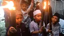Cahaya obor bambu yang dibawa peserta menerangi jalanan lingkungan permukiman, menghadirkan suasana hangat dan penuh kebersamaan di tengah masyarakat. Tampak dalam foto, anak-anak saat mengikuti pawai obor di kawasan Cinere,  Depok, Senin (16/2/2026). (merdeka.com/Arie Basuki)