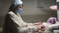 Seorang perawat memeriksa bayi Aleina Snizhana yang melahirkan di bangsal bersalin saat peringatan sirene untuk serangan udara di Mykolaiv, Ukraina pada 14 Maret 2022. Hampir setengah dari 49 perempuan harus melahirkan di ruang bawah tanah sejak 24 Februari lalu. (BULENT KILIC/AFP)