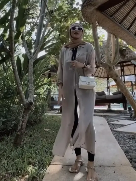 Olla mengenakan kemeja panjang pink transparan, dipadukan atasan dan celana hitam sebagai inner. Dan mengenakan kerudung coklatnya. [Instagram/@ollaramlan]