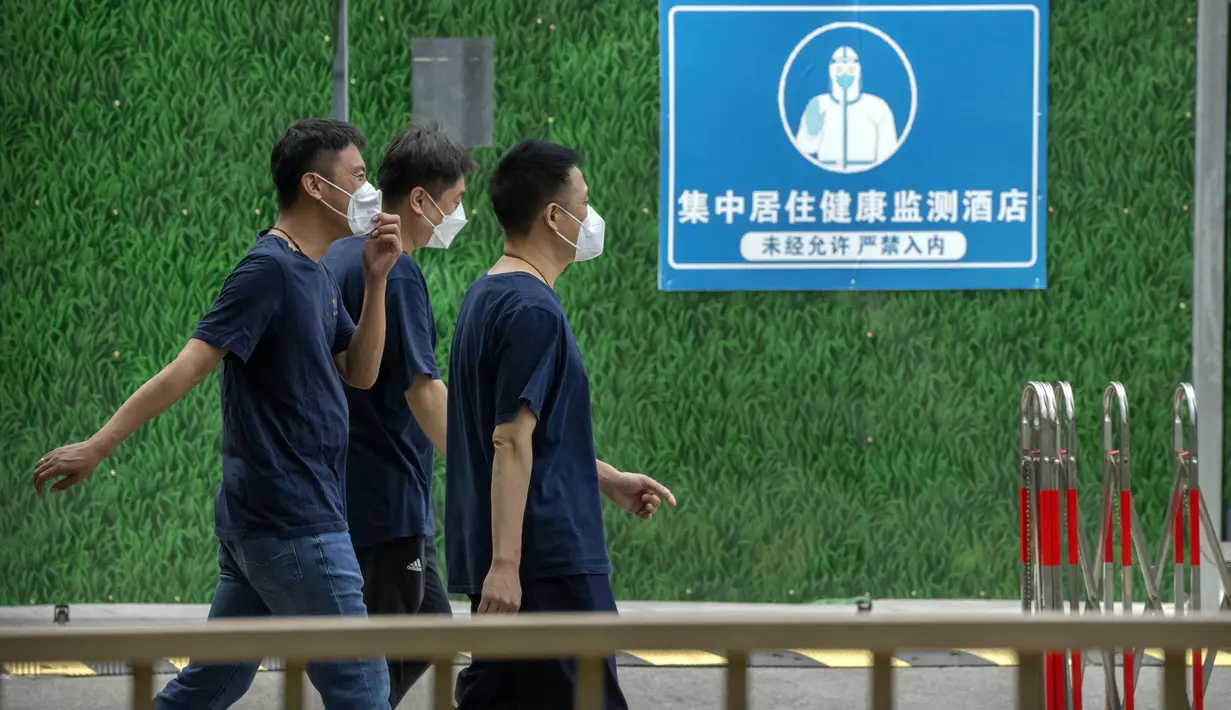 Orang-orang yang mengenakan masker berjalan melewati barikade di luar hotel karantina virus corona COVID-19 dengan tanda bertuliskan "Hotel pemantauan kesehatan perumahan terpusat - masuk tanpa izin sangat dilarang" di Beijing, China, 15 Juni 2022. (AP Photo/Mark Schiefelbein)
