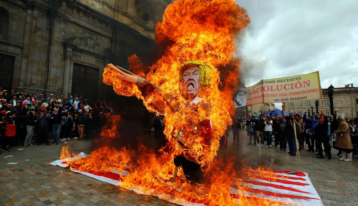 Para pengunjuk rasa membakar patung karakter Presiden AS Donald Trump saat melakukan aksi protes pada peringatan Hari Buruh di Bogota, Kolombia (1/5). Warga Kolombia merayakan Hari Buruh dengan membakan patung Donald Trump. (AP/Fernando Vergara)