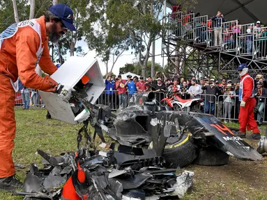 Seorang marshal mengosongkan kotak berisi puing mobil balap yang hancur akibat kecelakaan antara pembalap McLaren Fernando Alonso dan pembalap Haas, Esteban Gutierrez pada Formula 1 Grand Prix Australia di Melbourne, Minggu (20/3). (REUTERS/Joe Castro)
