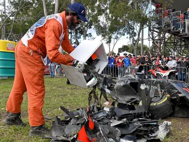 Seorang marshal mengosongkan kotak berisi puing mobil balap yang hancur akibat kecelakaan antara pembalap McLaren Fernando Alonso dan pembalap Haas, Esteban Gutierrez pada Formula 1 Grand Prix Australia di Melbourne, Minggu (20/3). (REUTERS/Joe Castro)