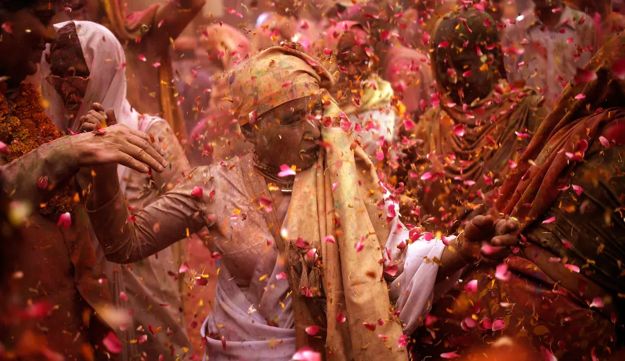 Para janda menari dan saling melempar serbuk berwarna dan kembang saat mengikuti tradisi perayaan Holi di Vrindavan, Uttar Pradesh, India (21/3). Holi merupakan salah satu festival perayaan awal musim semi terbesar di India. (REUTERS/Anindito Mukherjee)